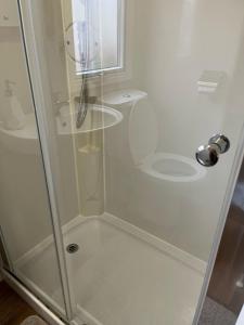 a shower with a glass door next to a toilet at Jay 28, California Cliffs, Parkdean, Sleeps Eight, Free Wi-Fi, Pet Friendly, Bed Linen and Towels Included in Great Yarmouth