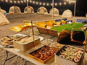 een tafel met verschillende dienbladen eten en tenten bij Overnight Musandam 20 tents whole Private camp for groups bathroom and kitchen in Al Frian