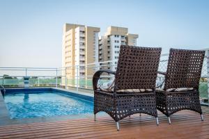 two chairs sitting on a deck next to a swimming pool at Hotel Ilha Costeira in São Luís