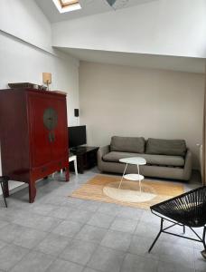 a living room with a couch and a table at Petite maison calme dans un jardin in Bois-Colombes