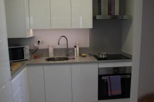 een keuken met witte kasten, een wastafel en een magnetron bij Amatista 12 D - Private in Calpe