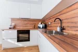 La cuisine est équipée de placards blancs et d'un évier en acier inoxydable. dans l'établissement Flex SelfCheckIns 143 - Novaki -Terrace - 4 Bedrooms - Parking, à Novaki Samoborski