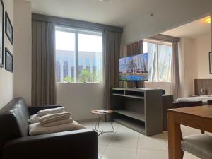 a living room with a couch and a television at Hotel Condominio Barretos Park Hotel in Barretos