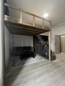 ブルノにあるCotton&Loft - Brno City Center Apartmentのロフトベッド1台(ソファ付)が備わる客室です。