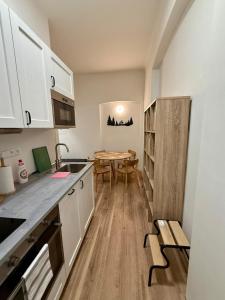 une cuisine avec des armoires blanches et une table à l'intérieur dans l'établissement Apartmán Pohoda - dvojlůžkový, v lázeňském centru, à Karlovy Vary