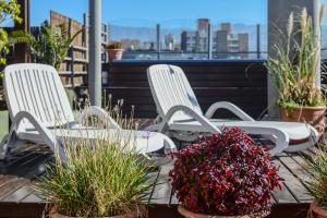 two white chairs sitting on a patio with plants at Portal Plaza Suites in Mendoza