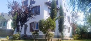 a white house with trees in front of it at Magnolia Homestay in Srinagar