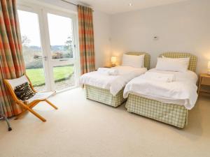 une chambre avec deux lits et une chaise et une fenêtre dans l'établissement Penarvon House - Stunning Waterfront Escape with Games Room, à Manaccan