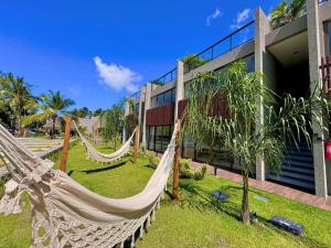 a resort with hammocks in front of a building at Villa Naluri - Casa Auati - Apart 2 Quartos -Vista Mar in Japaratinga