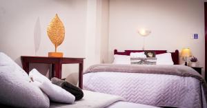 ein Schlafzimmer mit zwei Betten und einem Tisch mit Lampe in der Unterkunft UKUKU Hostel in Quito