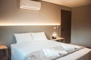 a bedroom with a white bed with two towels on it at Hotel San Marinho in União da Vitória