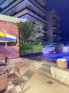 a patio with chairs and a swimming pool at night at Pousada Mariá in Cabo Frio +72 photos