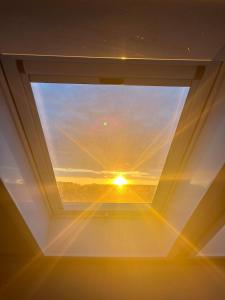 einen Blick auf den Sonnenuntergang durch ein Fenster in der Unterkunft Serene Loft Retreat in Münster + 1 Foto