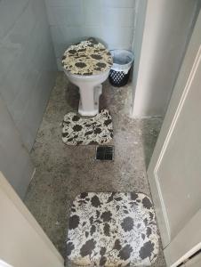 a bathroom with a toilet and two rugs on the floor at Vagas Carnaval AP no Centro de BH in Belo Horizonte