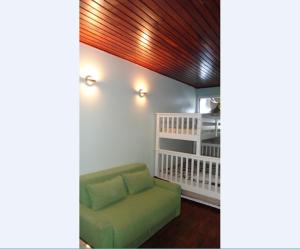 a living room with a green couch and a crib at Ajuricaba Suítes 7 in Manaus