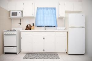 a white kitchen with a sink and a refrigerator at Tangerine Sunsets Skylark in Nassau +8 photos