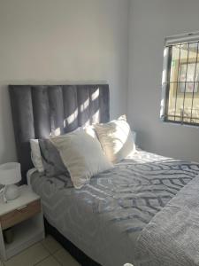 a bed with pillows on it in a bedroom at Beautiful 2 bedroom apartment in strand in Somerset West +10 photos