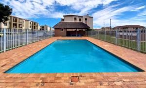 a large blue swimming pool with a fence at Beautiful 2 bedroom apartment in strand in Somerset West