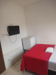 a room with a red bed and a tv on the wall at Pousada Iansã in Vera Cruz de Itaparica +43 photos