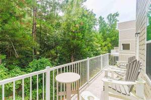 two chairs and a table on a balcony with trees at Family Fun House At Barefoot Resort & Golf in North Myrtle Beach