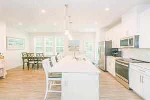 a kitchen with white cabinets and a table with chairs at Family Fun House At Barefoot Resort & Golf in North Myrtle Beach
