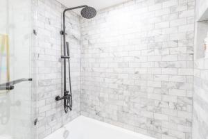 a bathroom with a shower with a white tile wall at Luxury DuPont Apartment in the heart of DC in Washington