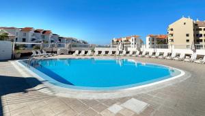 Una piscina en un patio con sillas y edificios. en Alda apartment, en Los Cristianos