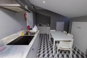 a kitchen with a sink and a table with chairs at ALM SANTA LUZIA in Guimarães