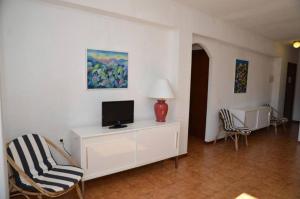 sala de estar con TV y 2 sillas en Costamar 15, en Es Pujols