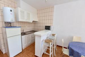 una pequeña cocina con electrodomésticos blancos y una mesa en Costamar 15, en Es Pujols