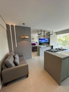 Una sala de estar con un sofá y una cocina. en Studio de Alto Padrão no Jardim Aquarius, en São José dos Campos