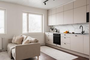 a kitchen with white cabinets and a couch in a room at Borg Itsenäisyydenkatu, Centre Spacious 2-Room Apt, King Bed, Free Parking & Wifi in Pori