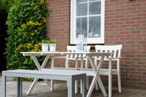 un tavolo bianco e sedie accanto a un edificio di Bed and Breakfast De Reggestee a Hellendoorn