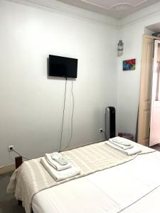 a bedroom with a bed and a flat screen tv on the wall at São Lázaro Bhuiyan Family Host in Lisbon
