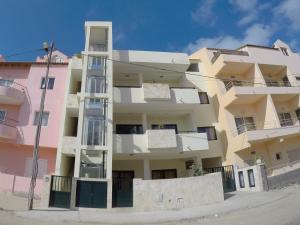 an apartment building with pink and yellow at Surf House Cabo Verde in Santa Maria