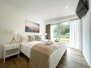 une chambre blanche avec un lit et une grande fenêtre dans l'établissement Haus-Nordseebrandung-FeWo-5, à Cuxhaven