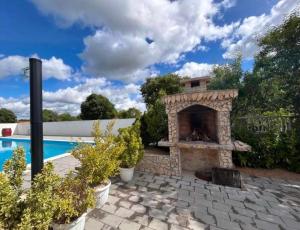 a patio with a stone fireplace next to a swimming pool at Schönes Ferienhaus mit Pool in Biograd na Moru