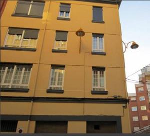 un grand bâtiment jaune avec des fenêtres et une horloge. dans l'établissement Leon Apartamento Centro, à León