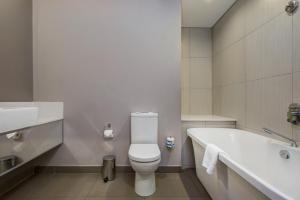 a white toilet sitting next to a sink in a bathroom at ANEW Hotel Hatfield Pretoria in Pretoria