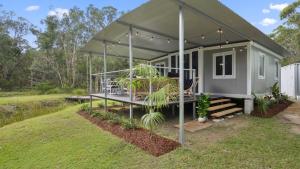 a tiny house with a canopy in a yard at Leo's Beach Hideaway - Stylish Tiny Home in Arrawarra