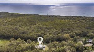 an aerial view of a building in a forest with the ocean at Leo's Beach Hideaway - Stylish Tiny Home in Arrawarra