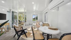 a living room with a couch and a table and chairs at Leo's Beach Hideaway - Stylish Tiny Home in Arrawarra