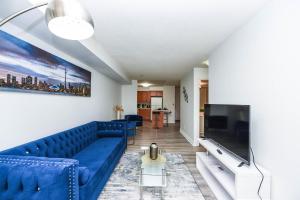 a living room with a blue couch and a large tv at Amazing 2BR & 2BTH - Near Square One Mall in Mississauga
