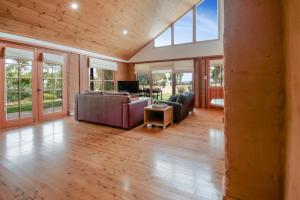 ein Wohnzimmer mit einem Sofa, einem TV und Fenstern in der Unterkunft Little Bunda Cottage - Charming Mudbrick Stay in Bomen