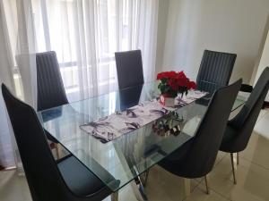a glass dining table with black chairs and a vase of flowers at Luxury 0ne in Trevallyn