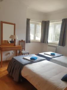 a bedroom with two beds and a desk and a mirror at Casa das Oliveiras - Manteigas in Manteigas