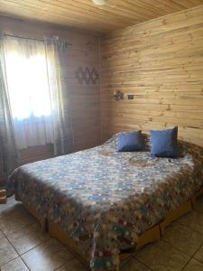 a bedroom with a bed with blue pillows and a window at Casa equipada para 8 personas in Boca Pupuya