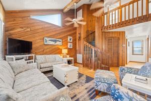 Una sala de estar con un sofá y un televisor. en Summer Days 4 Bedroom Oceanfront Home, en Kill Devil Hills