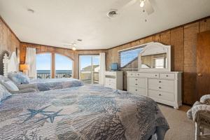 Un dormitorio con dos camas y un espejo. en Summer Days 4 Bedroom Oceanfront Home, en Kill Devil Hills