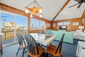 un comedor con mesa y sillas y un dormitorio en Summer Nights 4 Bedroom Oceanside Home, en Kill Devil Hills